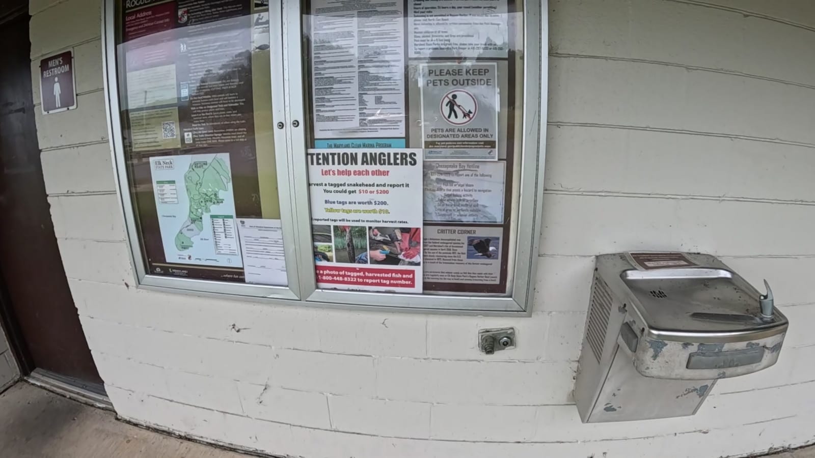 Harbor restroom building with a men's restroom sign and posted notices