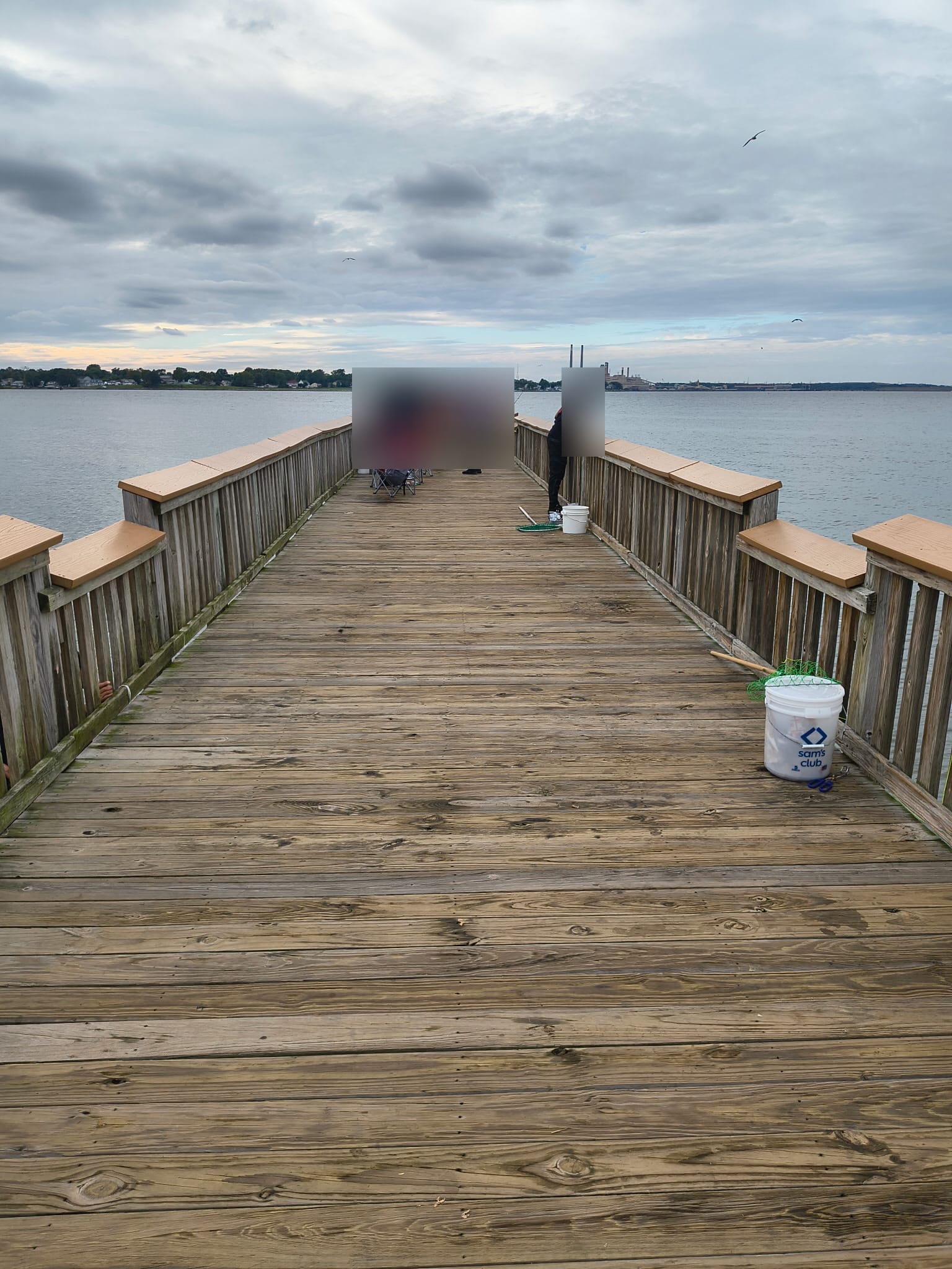 Looking along the timber pier toward the water. This photo does not identify catch species or water depth. Visitors have been obscured.