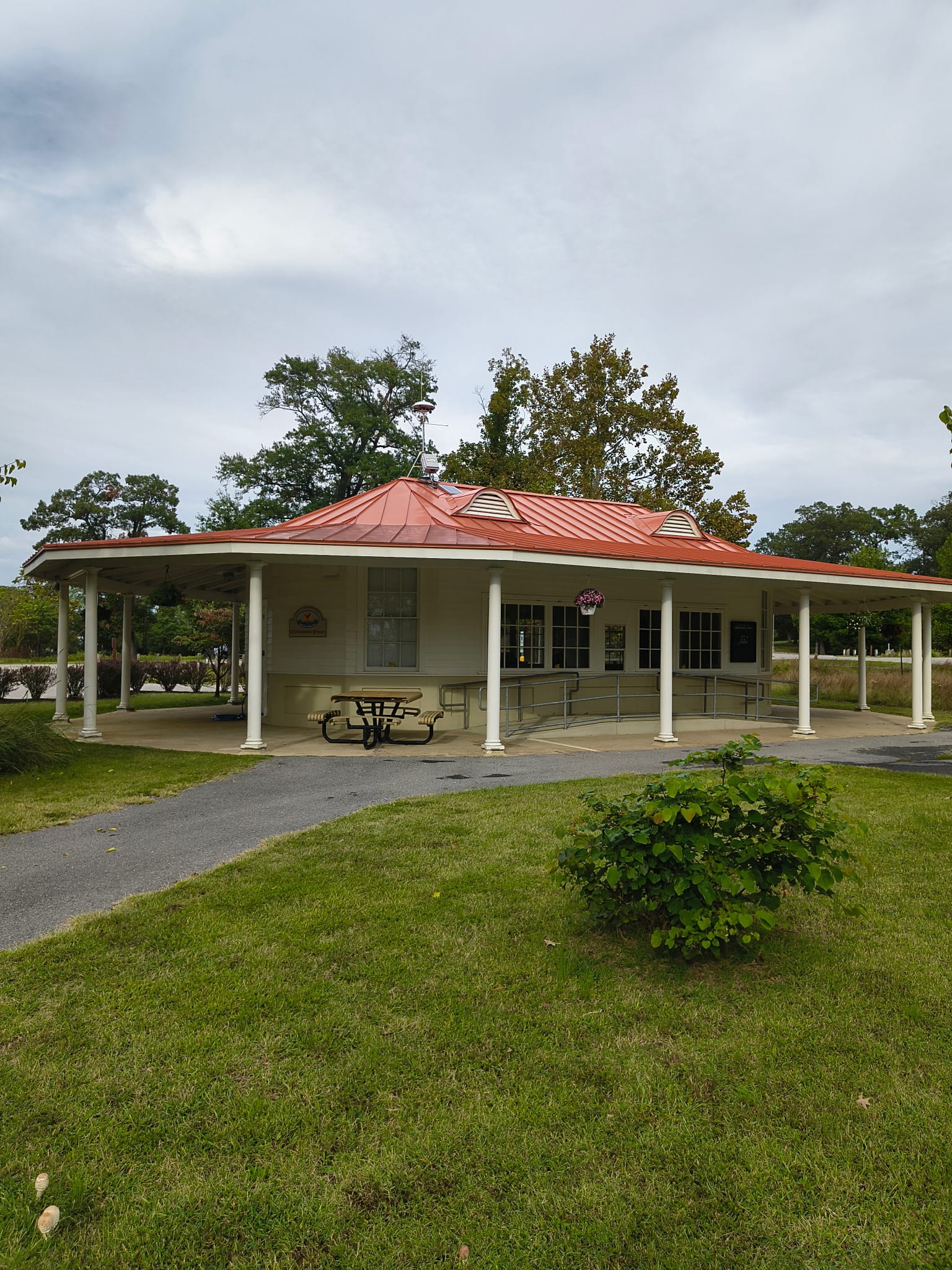 A park building with a covered picnic table and exterior ramp. This photo does not establish restroom opening hours or full-route accessibility.