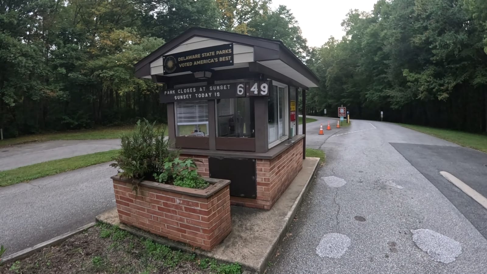 The entrance booth reminds visitors that the park closes at sunset; the displayed sunset time changes with the date.
